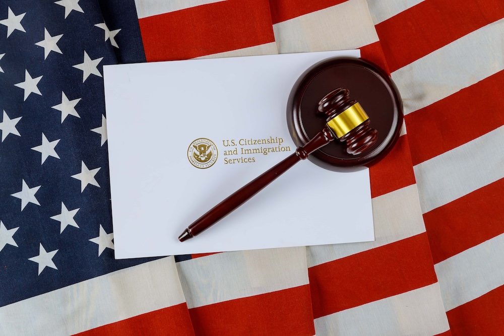 A wooden gavel on a desk in a law office, with a small American flag nearby, representing legal matters like deportation and U.S. citizenship;
