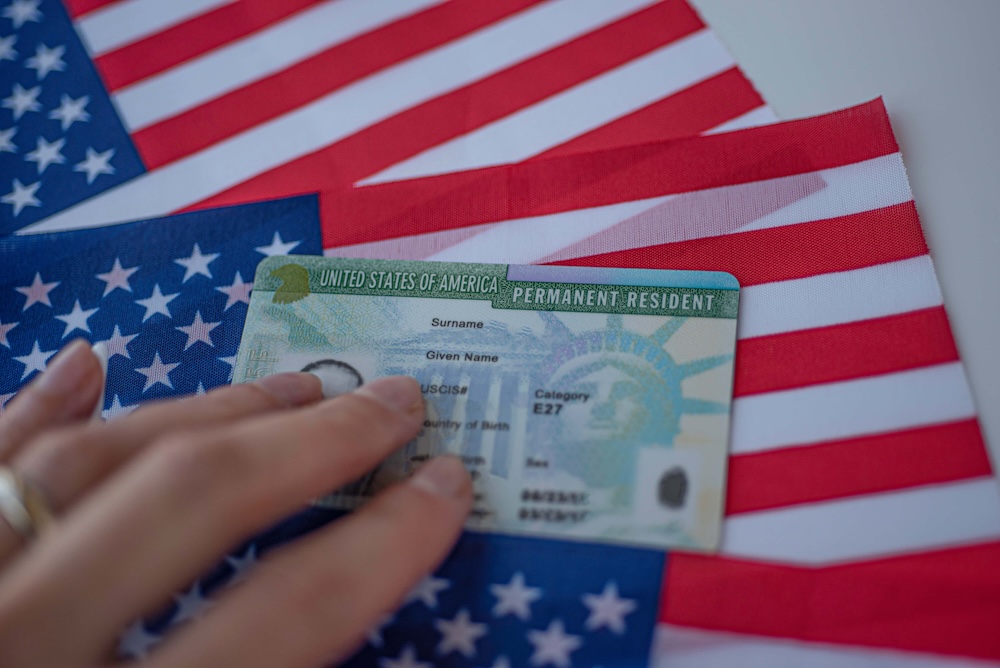 Permanent Resident Green card of United states of America on flag of USA. Above close up view